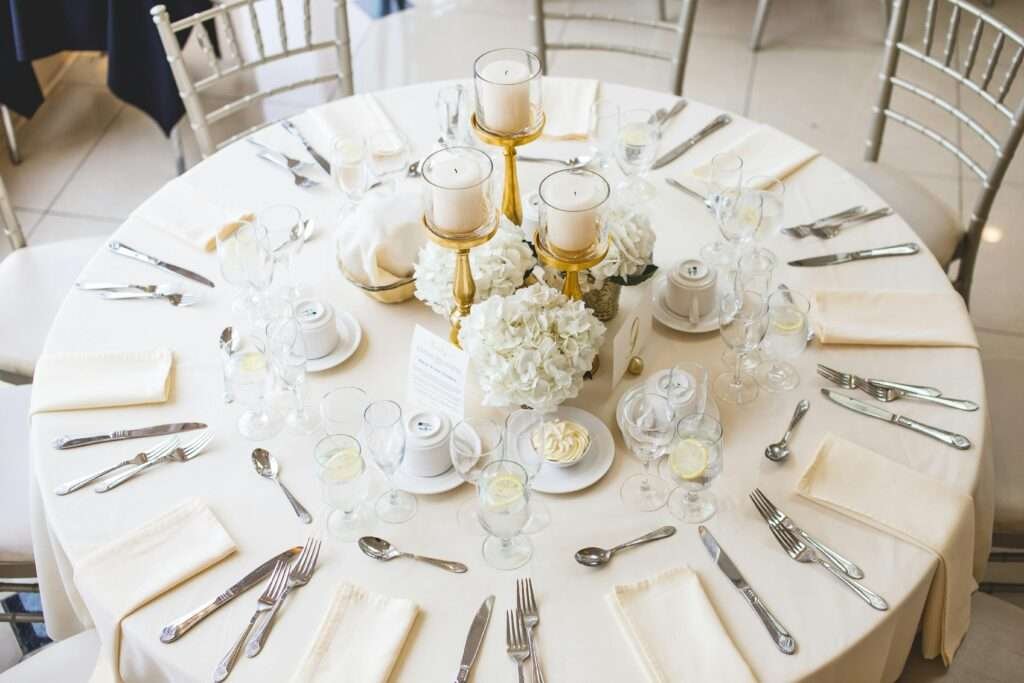 Beautifully arranged dining table setting with candles and floral centerpiece, perfect for a wedding reception.